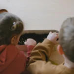 Dos niños pequeños sembrando semillas en contenedor con tierra en casa